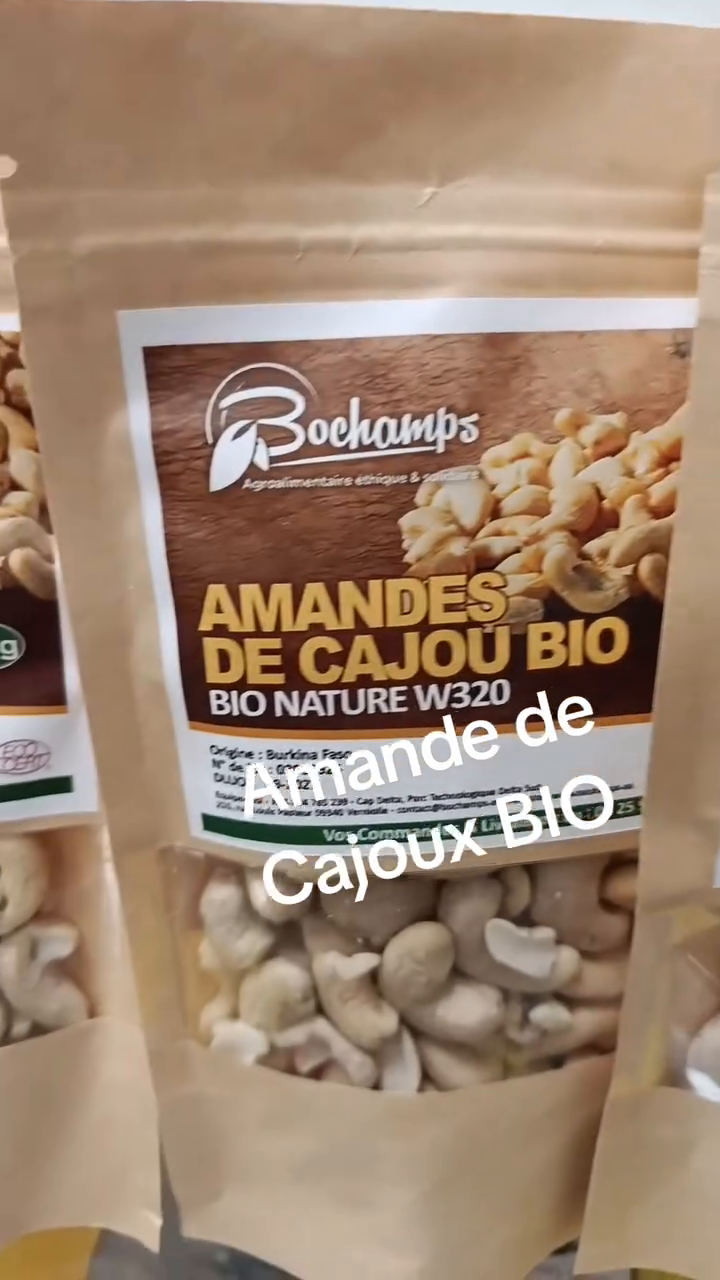 Gros plan sur des sachets kraft d'amandes de cajou bio de la marque Bochamps, origine Burkina Faso, avec les noix de cajou visibles a travers la fenetre de l'emballage.